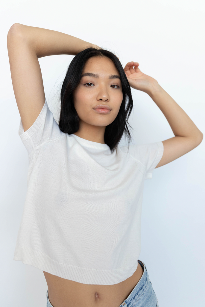 model wearing white INTACT merino wool tee stretching arms 